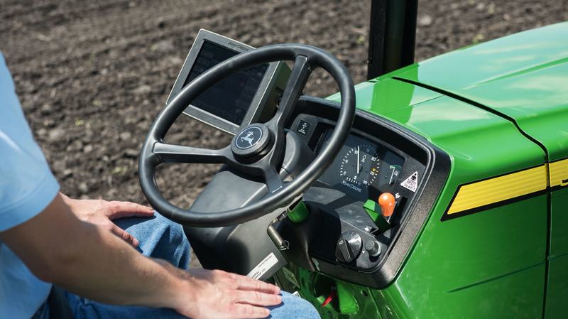 Operador usando AutoTrac Universal en un tractor John Deere