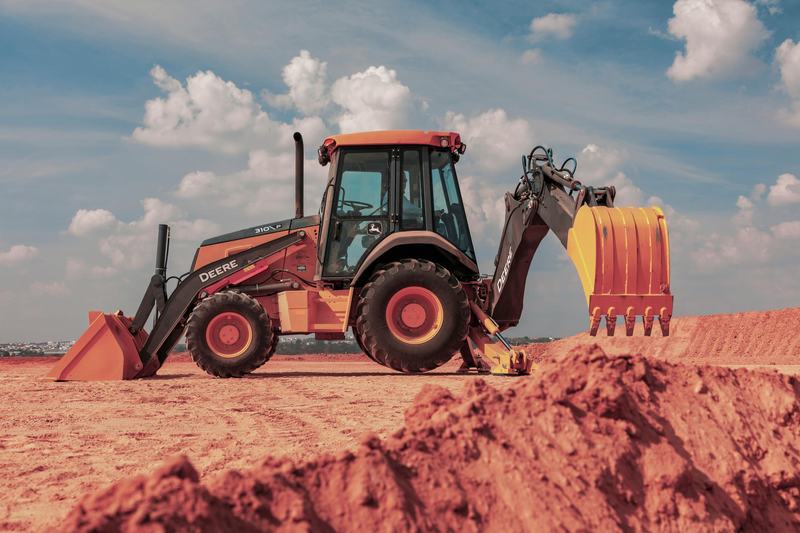 Retroexcavadora John Deere 310P en una obra sobre tierra roja