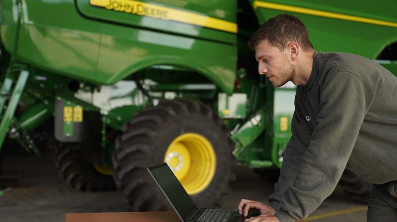 Técnico conectando su computadora a una cosechadora John Deere para diagnosticarla
